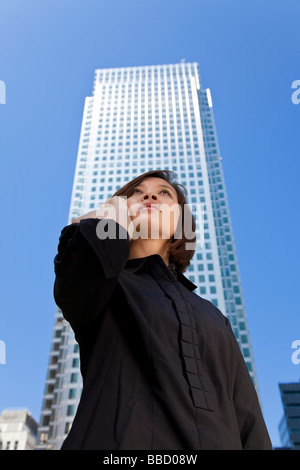 Eine schöne junge orientalische Frau mit einer wunderbar auf ihr Handy in einem modernen Hochhaus gefüllt Stadt Stockfoto