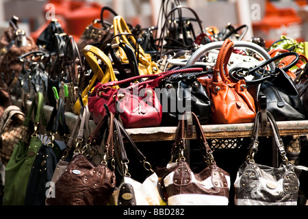 Handtaschen in verschiedenen Farben und Materialien, die gestapelt auf einem shopping Stand auf einer Straße in New York Stockfoto
