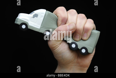 EIN LKW GEQUETSCHT IN A MANS HAND ILLUSTRIERT, REZESSION UND WIRTSCHAFTLICHE SITUATION DER TRANSPORT BRANCHE, GROßBRITANNIEN. Stockfoto