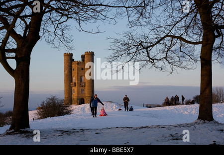 Umgeben von Schnee, Broadway Tower in Gloucestershire von den letzten Strahlen der Sonne an einem kalten Wintertag leuchtet Stockfoto