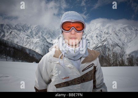 Einen weiblichen Snowboarder mit Orange Brille steht vor der majestätischen Berge in Nagano, Japan Stockfoto