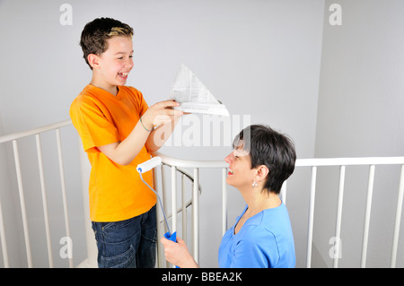 Lackierung, junge seiner Mutter Kopf einen Papierhut aufsetzen Stockfoto