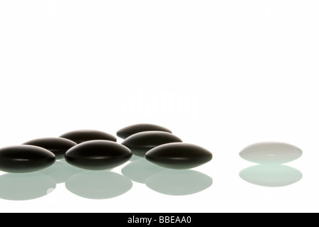 Weiße Linsen gegen schwarze Linsen, symbolisch für Odd Man Out, das Anderssein Stockfoto