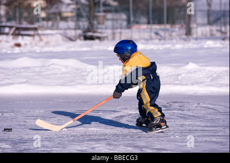 Kleiner Junge spielt Hockey auf einem zugefrorenen Teich, Fuschlsee, Salzburger Land, Österreich Stockfoto