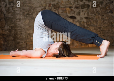 Frau in Yoga-Klasse tut Pflug-Pose Stockfoto