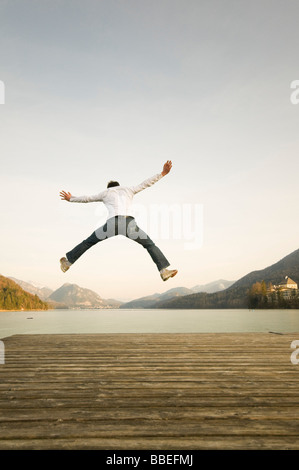 Mann am Dock springen hoch in die Luft, Fuschlsee, Salzburger Land, Österreich Stockfoto