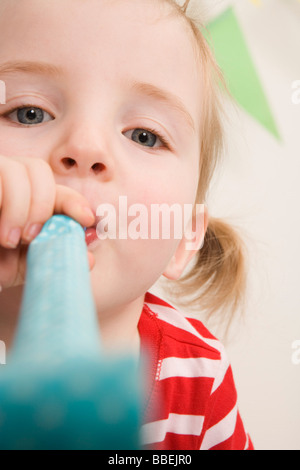 Kleines Mädchen bläst ein Krachmacher auf einer Geburtstagsfeier Stockfoto