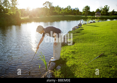 Frau auf der Suche nach Golfball im Wasser, Burlington, Ontario, Kanada Stockfoto