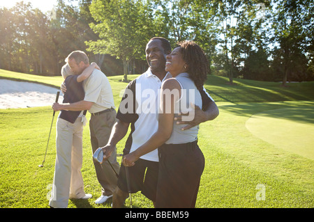 Paare, die umarmt auf Golfplatz Stockfoto