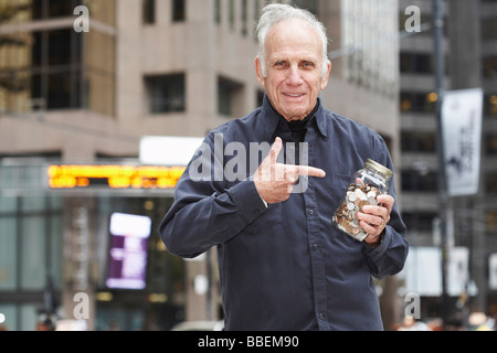 Portrait of Man Holding Jar von Münzen Stockfoto