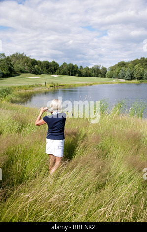 Rückansicht der Frau Golfen in hohe Gräser Stockfoto