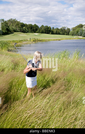 Seitenansicht der Frau Golfen in hohe Gräser Stockfoto