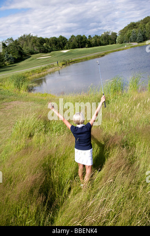 Rückansicht der Frau Golfen in hohe Gräser Stockfoto