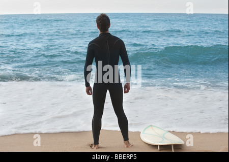 Surfer im Neoprenanzug stehen am Strand Stockfoto