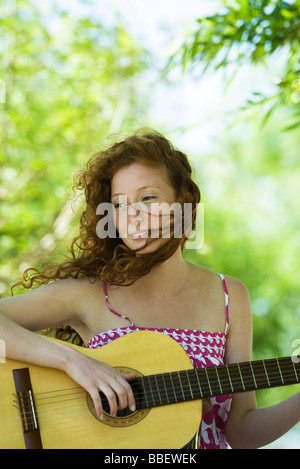 Junge Frau spielt akustische Gitarre im freien Stockfoto