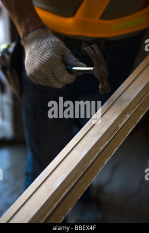 Arbeiter mit Hammer gegen Holz Stockfoto