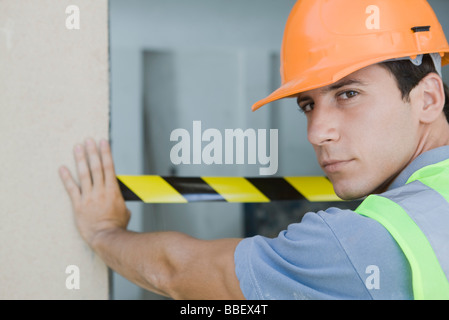 Arbeiter platzieren Sicherheit Band über Tür, über die Schulter in die Kamera schaut Stockfoto