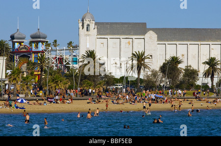 Australien, Melbourne, Victoria, St Kilda. Menschen auf St. Kilda Beach mit dem Palais Theater und Luna Park hinter. Stockfoto