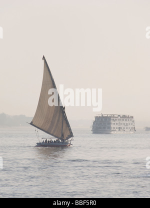 Eine Feluke (ägyptischen Segelboot) geht vor Kreuzfahrtschiff auf dem Nil. Luxor, Ägypten. Stockfoto