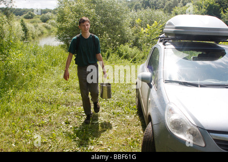 Gerne hoch Junge automotive Touristische bereitet für das Kochen von Hoper Fluss in Penza Region in Russland Durchführung einen Eimer mit Wasser aus dem Fluss Stockfoto