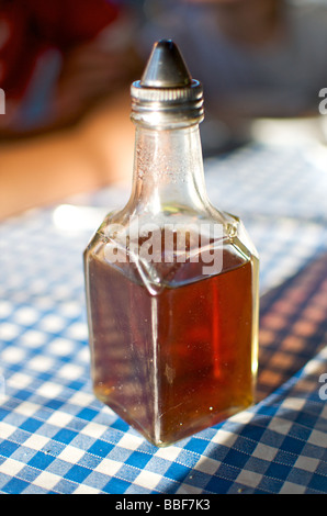 Eine altmodische Essig Flasche stand auf einem blauen und weißen Gingham check table Tuch in eine traditionelle britische Cafe Stockfoto