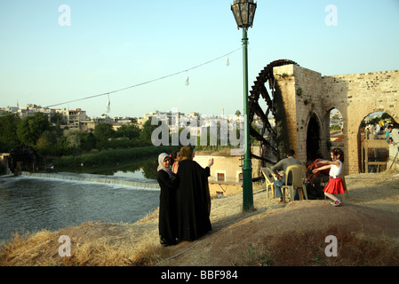 Muslimische Frauen in der Nähe von einem Wasserrad oder Noria am Fluss Orontes Stockfoto