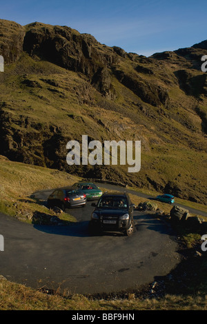 Autofahrer kämpfen, um die Kurven auf den Steilstrecken Hardknott Pass im Lake District zu verhandeln Stockfoto