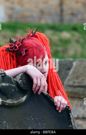 Ein Goth mit gefärbten roten Haaren auf dem Gelände des St. Marys Kirche, Whitby Whitby "Goth" Wochenende Stockfoto