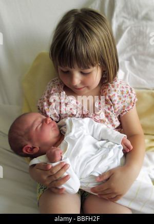 Vier Jahre alte Schwester glücklich hielt sie einen Tag alt Baby Bruder Stockfoto