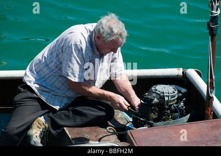 Ein Fischer, der Außenbordmotor auf seinem kleinen Fischerboot zu reparieren. Stockfoto