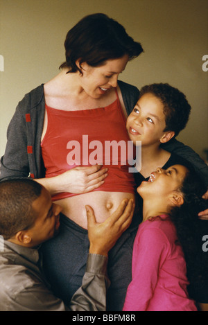 Mann und Kinder versammelten sich um schwangere Frau, Lächeln Stockfoto