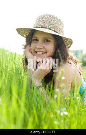 Porträt eines lächelnden Mädchens tragen einen Sonnenhut auf einer Wiese liegend Stockfoto