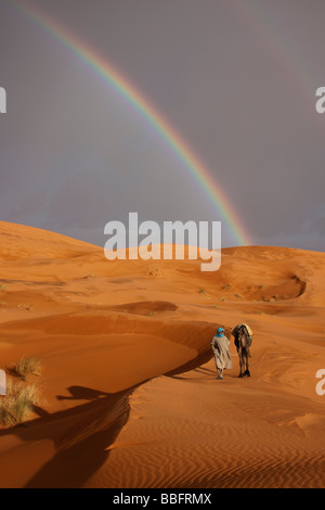 Afrika, Nordafrika, Marokko, Sahara Wüste, Merzouga, Erg Chebbi, Berber Tribesman führenden Kamel, Regenbogen in der Wüste Stockfoto