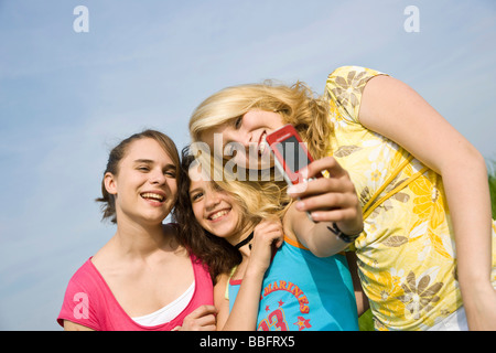 Drei lachende Mädchen, die ein Foto von sich mit einem Mobiltelefon Stockfoto
