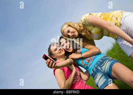 Drei lachende Mädchen, die ein Foto von sich mit einem Mobiltelefon Stockfoto