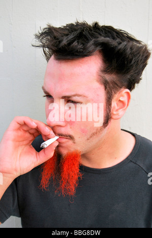 Drogen, junger Mann mit rot-schwarzen Bart, eine gemeinsame, handgerollte Zigarette rauchen Stockfoto
