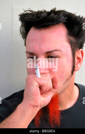 Rauchen Unkraut, junger Mann mit rot-schwarzen Bart eine gemeinsame, handgerollte Zigarette rauchen Stockfoto
