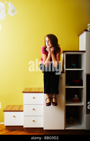 Junges Mädchen sitzen auf den Stufen einer Kommode Stockfoto