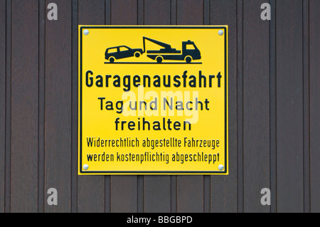 Gelbes Schild am Garagentor, halten Sie die Garage Ausfahrt erreichbar Tag und Nacht, widerrechtlich geparkten Fahrzeuge kostenpflichtig abgeschleppt werden Stockfoto