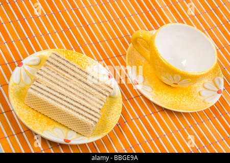 Waffel-Stück und Tasse mit Kaffee auf Bambus-Tischdecke hautnah Stockfoto