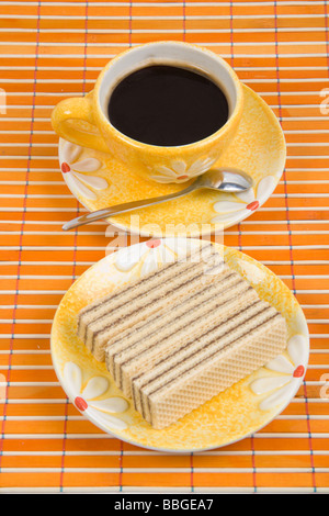 Waffel-Stück und Tasse mit Kaffee auf Bambus-Tischdecke hautnah Stockfoto