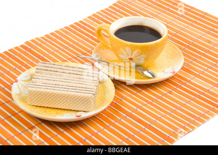 Waffel-Stück und Tasse mit Kaffee auf Bambus-Tischdecke hautnah Stockfoto