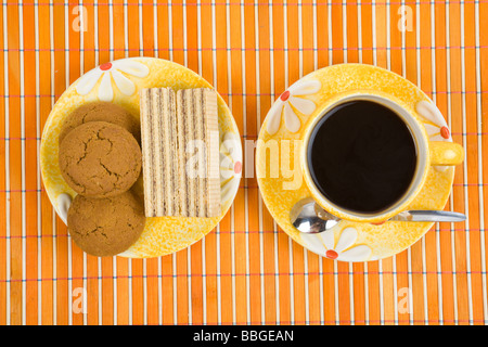 Waffel-Stück und Tasse mit Kaffee auf Bambus-Tischdecke hautnah Stockfoto