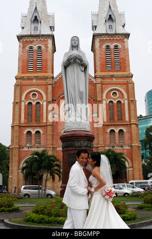 Hochzeitspaar posiert für Fotos von Statue der "Jungfrau Maria", die Kathedrale "Notre Dame", "Ho Chi Minh" Stadt, Saigon, Vietnam Stockfoto