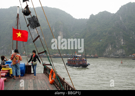 Vietnamesisch [rote Fahne] und Touristen auf dem Deck des Junk-e-Boot Segeln in [Halong Bay], Vietnam Stockfoto