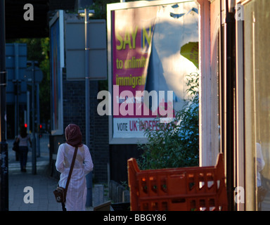 Junge muslimische Frau geht vorbei ein UKIP-Plakat lesen "Nein sagen zu unbegrenzten Einwanderung". Stockfoto