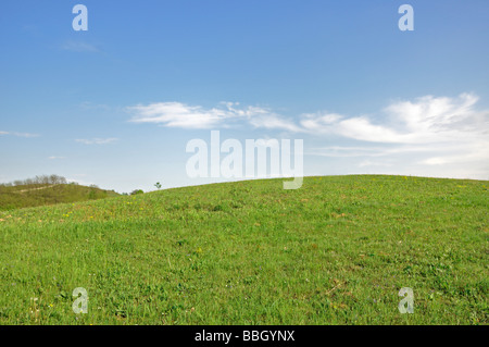 Wolken am blauen Himmel über grasbewachsene Hügel Stockfoto