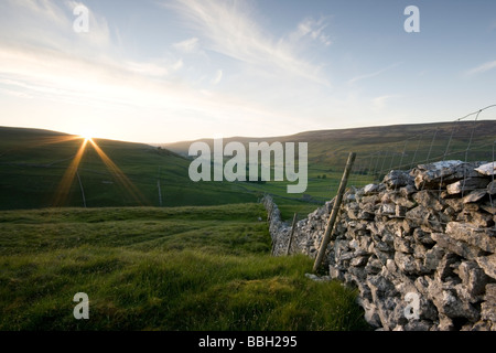 Sonnenuntergang und eine Trockensteinmauer führt das Auge entlang Littondale, in den Yorkshire Dales, von oben das Dorf Arncliffe. Stockfoto