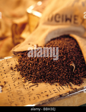 Geröstete Kaffeebohnen aus Leinensack auf Quader. Stockfoto