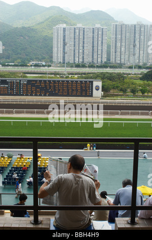 Chinesischer Mann Racing Zeitunglesen im Sha Tin Race Course Hong Kong Stockfoto